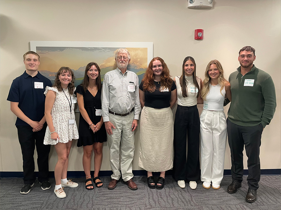 Eight people in a row, including seven interns and a funder representative