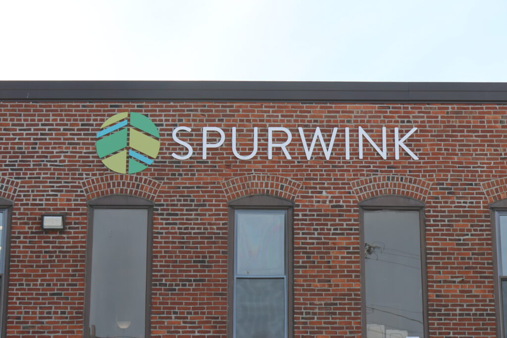 Exterior of a brick building with the Spurwink logo