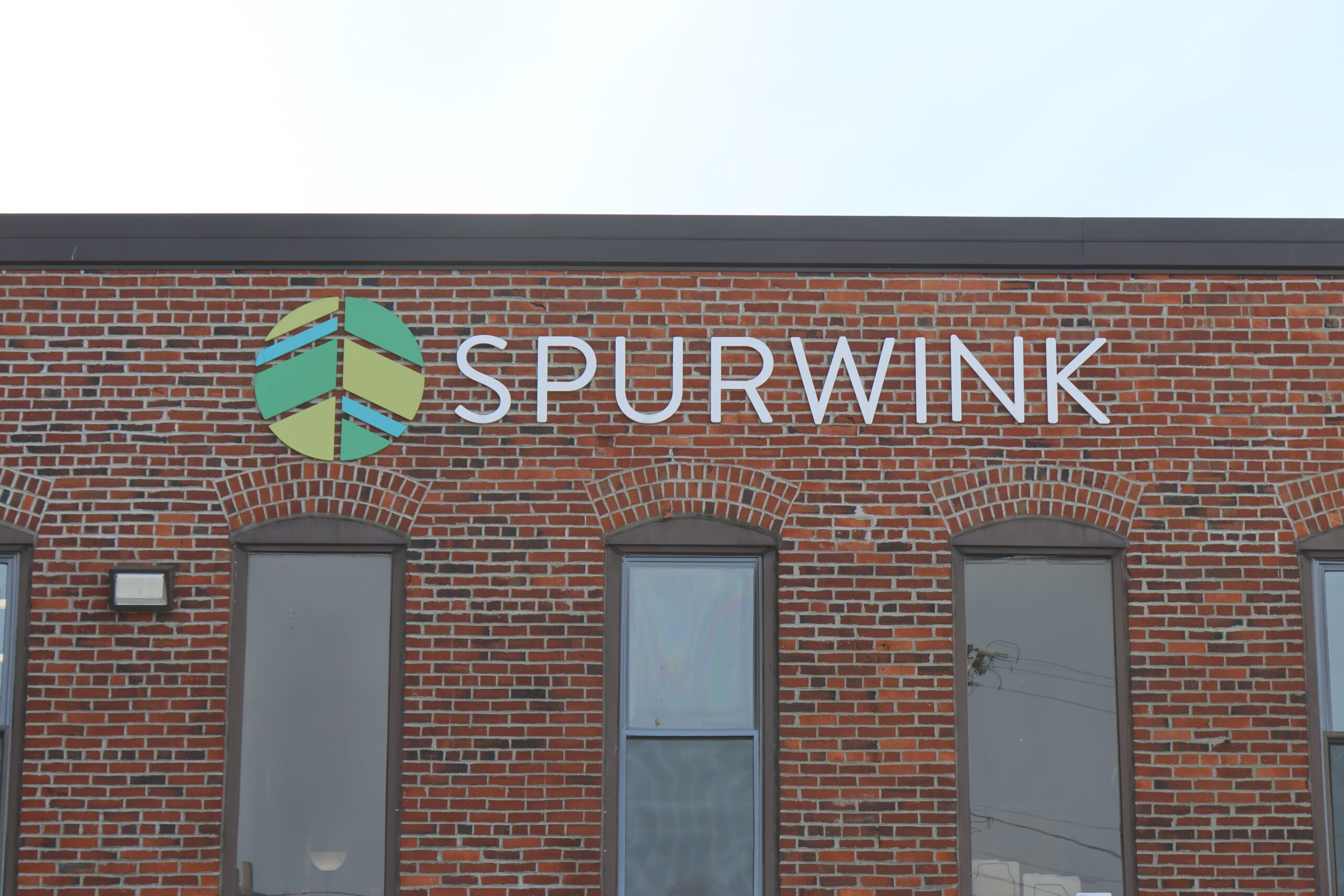 Exterior of a brick building with the Spurwink logo