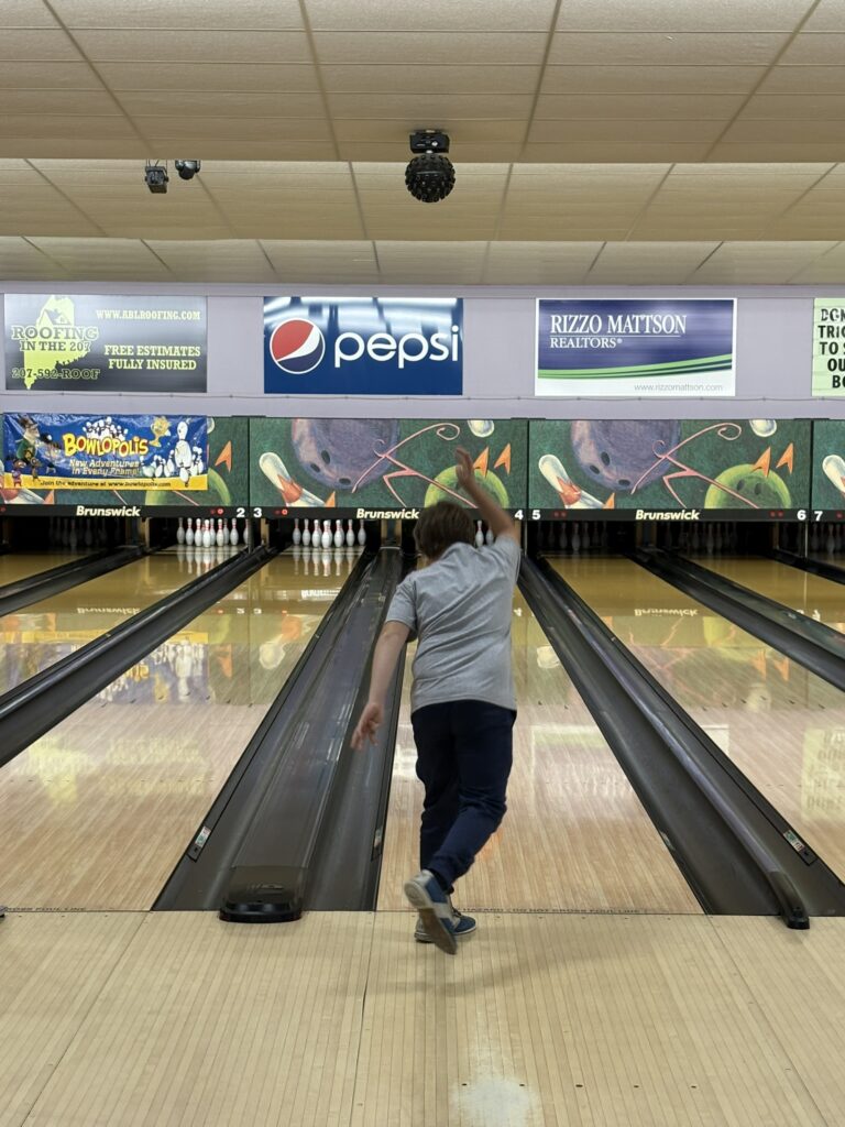 A child throws a bowling ball down a bowling lane.