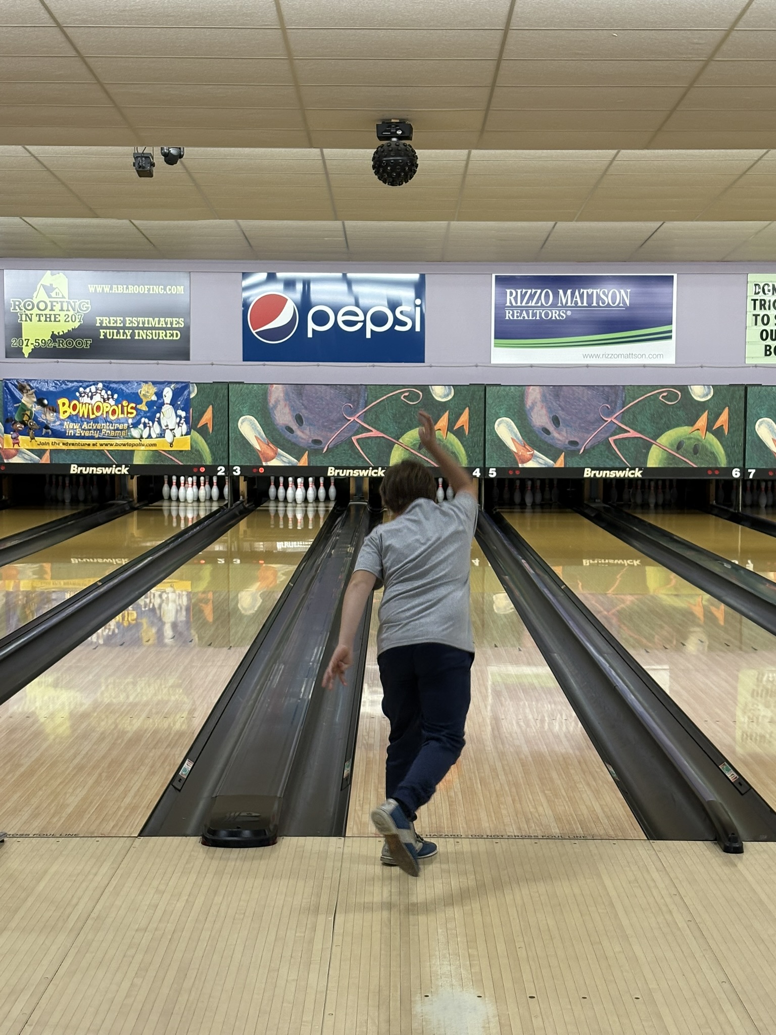 A child throws a bowling ball down a bowling lane.