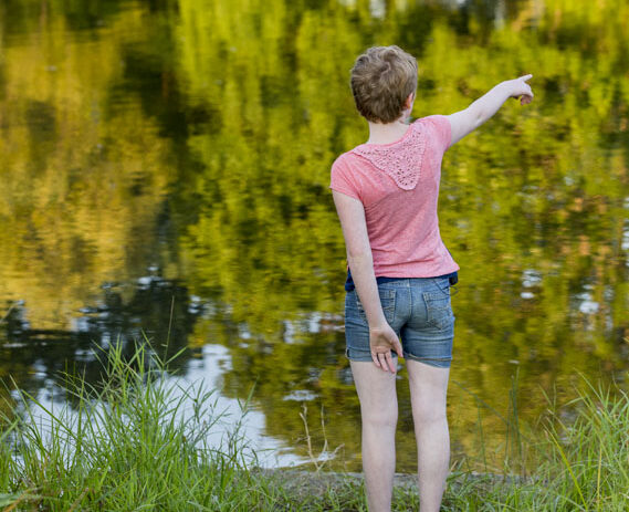 A child stands by the edge of a lake.