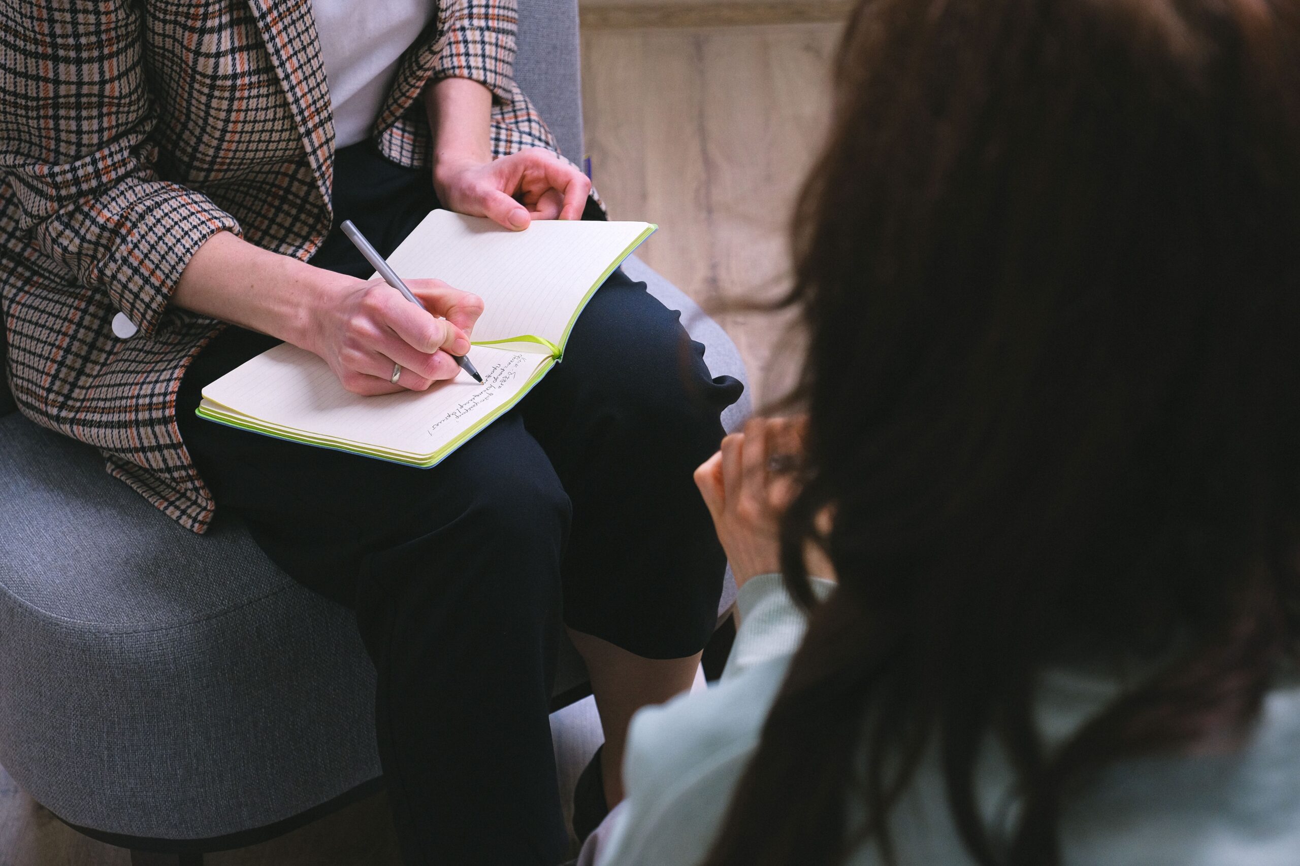 Photo of a therapist taking notes while talking to a patient.
